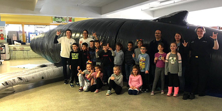 children and teach in front on the inflatable life size humpback whale model